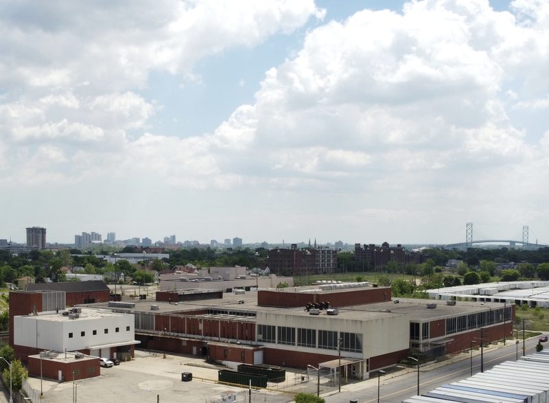 Present-day aerial view of the Scotten Street campus from the west, with the Detroit skyline and Ambassador Bridge in the distance