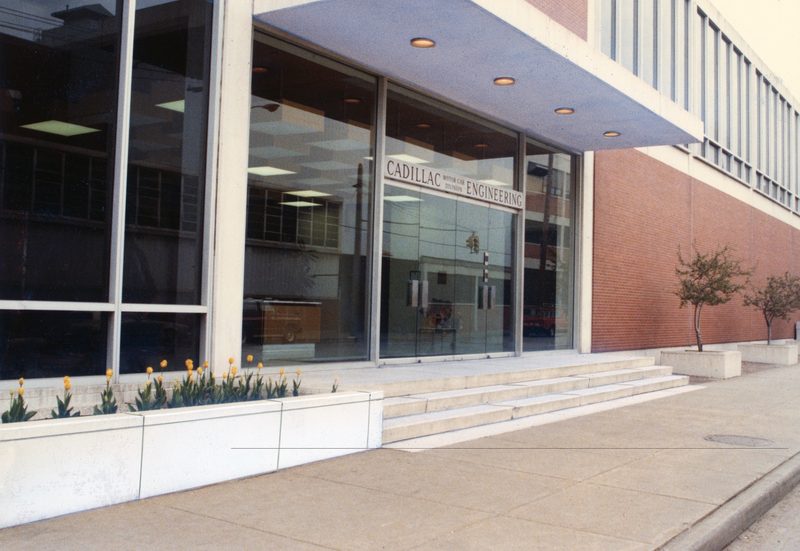 Color photograph of the Cadillac Engineering entrance with spring tulips and a modernist glass and steel facade